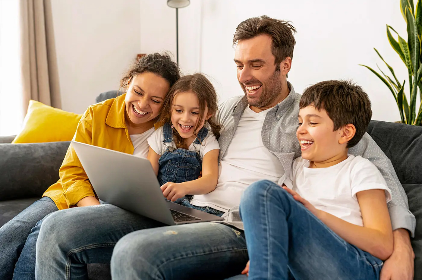 family sat smiling around a laptop